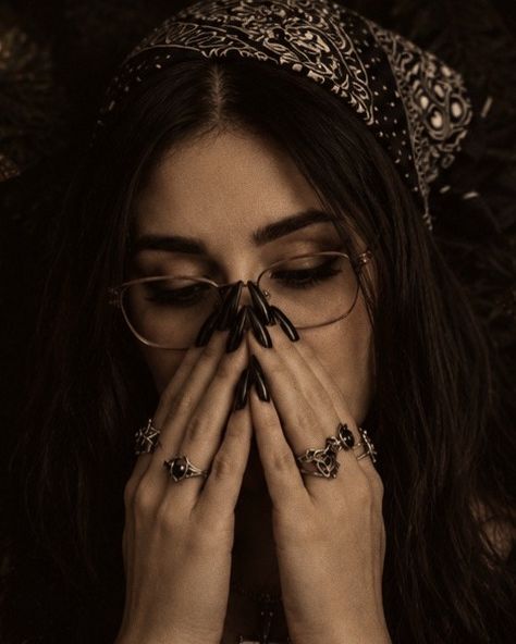 Close-up of Trisha Marie in a bandana and glasses, hands raised to her face.