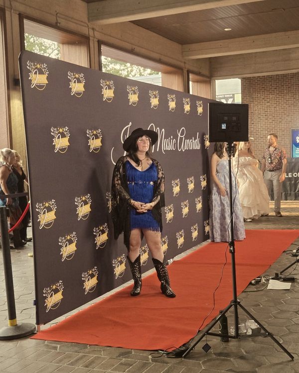 Trisha Marie on the red carpet at the 2026 Josie Music Awards, in a blue dress, cowboy hat and boots.