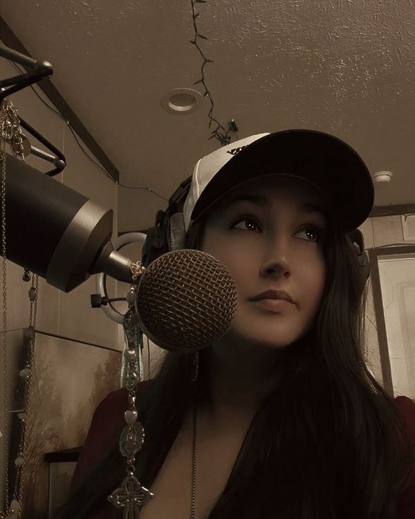 Trisha Marie in a cap at the microphone in her home studio.